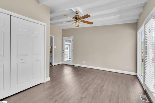 unfurnished bedroom with visible vents, beamed ceiling, and baseboards