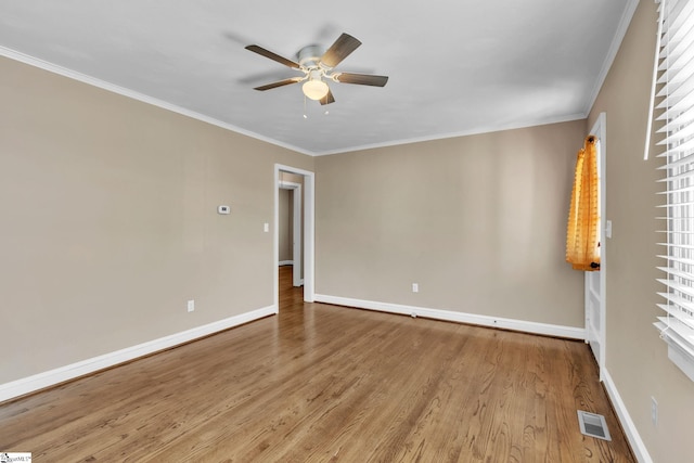 empty room featuring ornamental molding, wood finished floors, visible vents, and baseboards