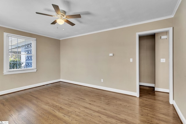 empty room with ornamental molding, ceiling fan, baseboards, and wood finished floors