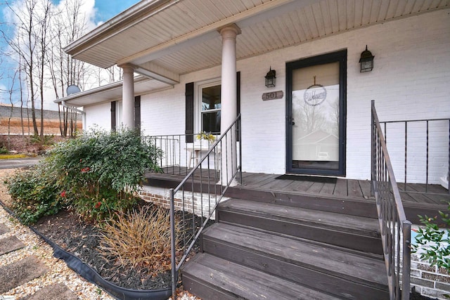 property entrance with a porch and brick siding