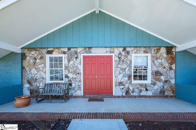 view of exterior entry with stone siding and a porch