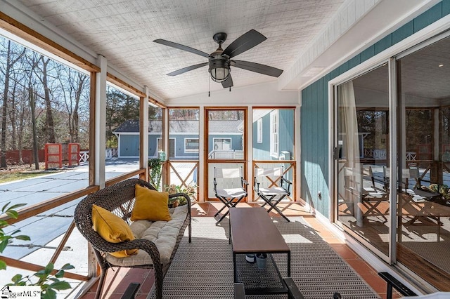 unfurnished sunroom with a ceiling fan, lofted ceiling, and plenty of natural light