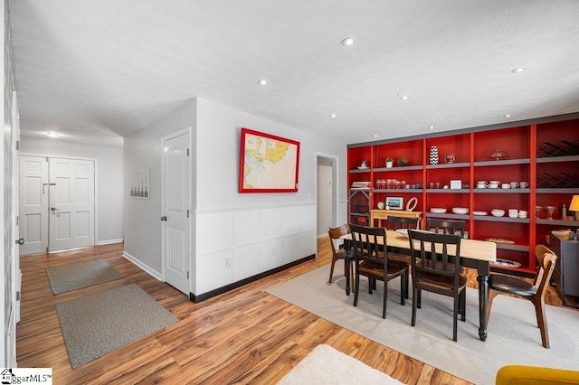 dining room featuring baseboards, built in features, wood finished floors, and recessed lighting