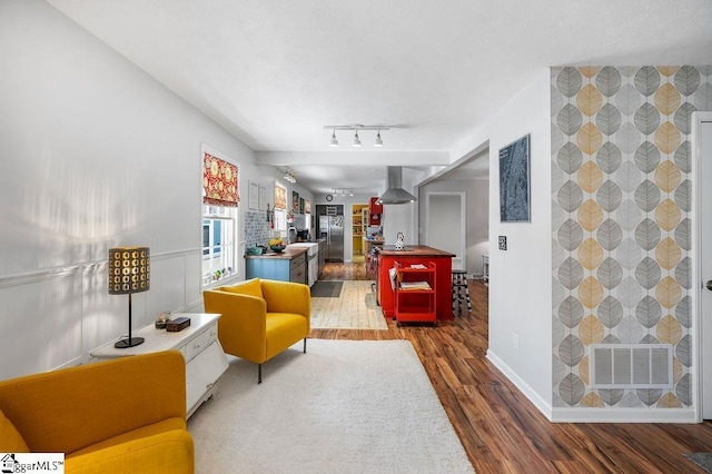 interior space with rail lighting, visible vents, an accent wall, wood finished floors, and baseboards