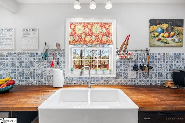 kitchen featuring black dishwasher, butcher block countertops, and a sink