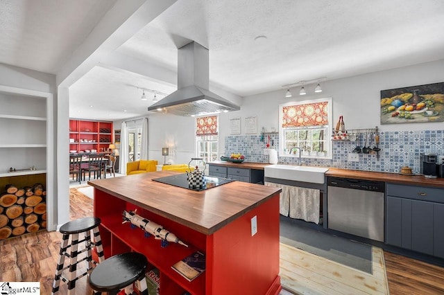 kitchen with butcher block counters, stainless steel dishwasher, a sink, island range hood, and black electric cooktop