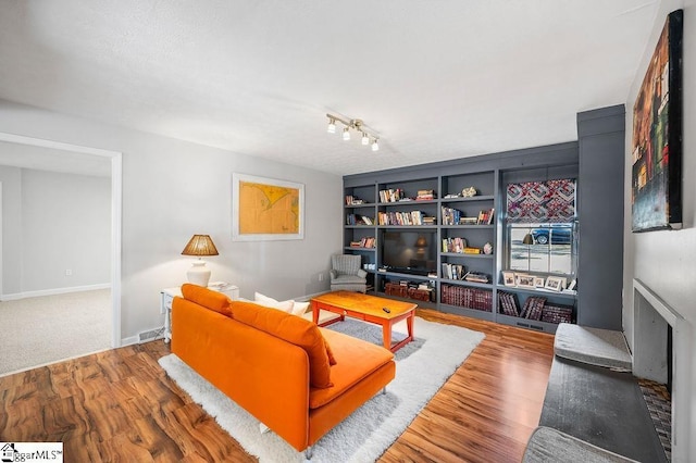 living room with built in shelves, baseboards, and wood finished floors