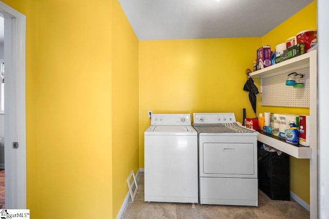 laundry area with laundry area, independent washer and dryer, visible vents, and baseboards