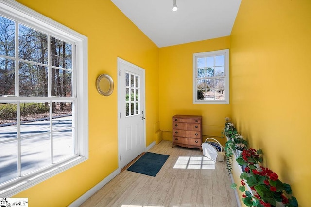 doorway to outside featuring vaulted ceiling, baseboards, and wood finished floors