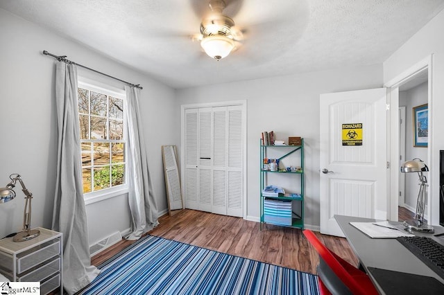 bedroom with a textured ceiling, a closet, baseboards, and wood finished floors