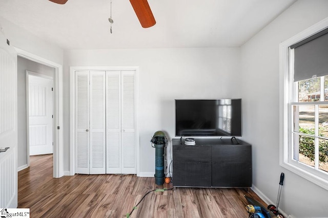 living room with a ceiling fan, baseboards, and wood finished floors