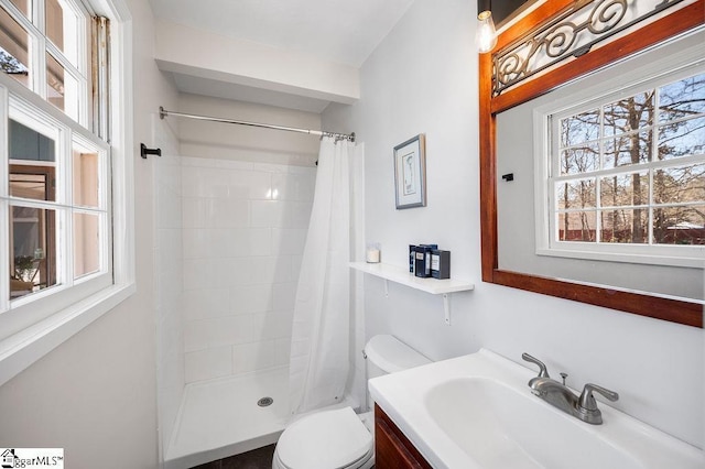 full bath with a tile shower, vanity, and toilet