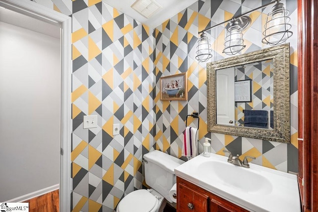 bathroom with visible vents, vanity, toilet, and wallpapered walls