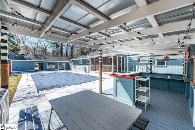 view of swimming pool featuring an outbuilding, a covered pool, outdoor dry bar, and a wooden deck