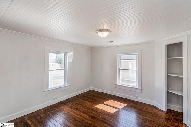 unfurnished room with dark wood-style floors, baseboards, visible vents, and crown molding