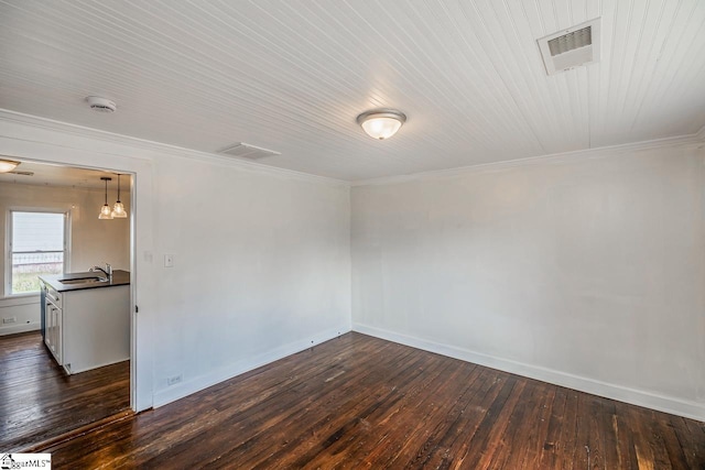 empty room with ornamental molding, dark wood-type flooring, a sink, and visible vents