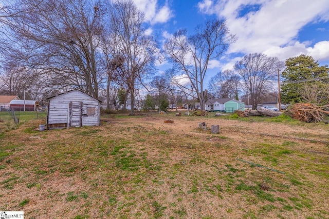 view of yard with an outdoor structure, fence, and a storage unit