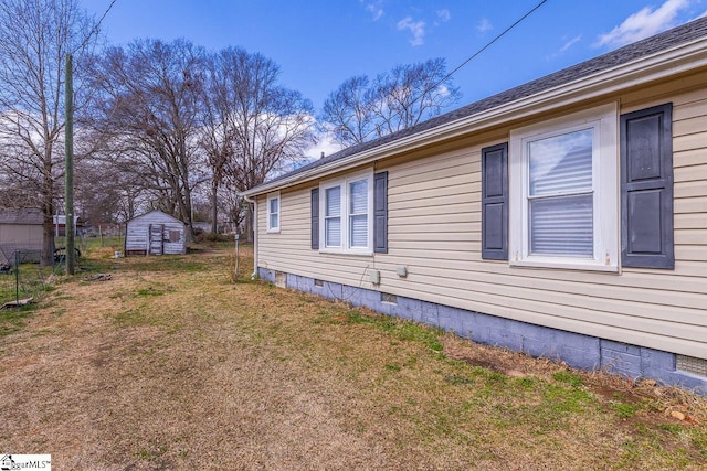 view of side of home featuring a shingled roof, an outbuilding, crawl space, a yard, and a shed