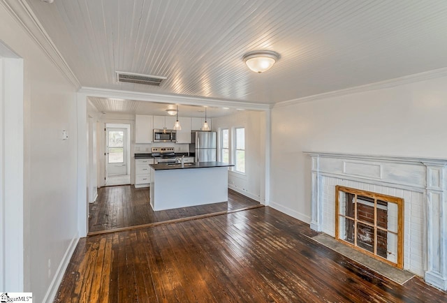 kitchen with dark wood finished floors, dark countertops, a fireplace with flush hearth, appliances with stainless steel finishes, and white cabinetry