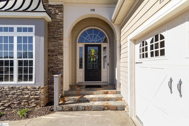 entrance to property with a garage and stone siding