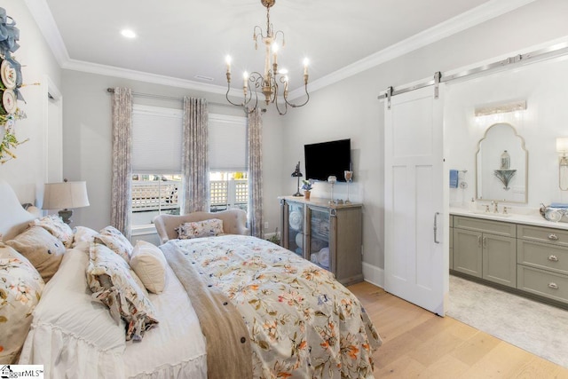 bedroom with light wood finished floors, a barn door, connected bathroom, an inviting chandelier, and crown molding