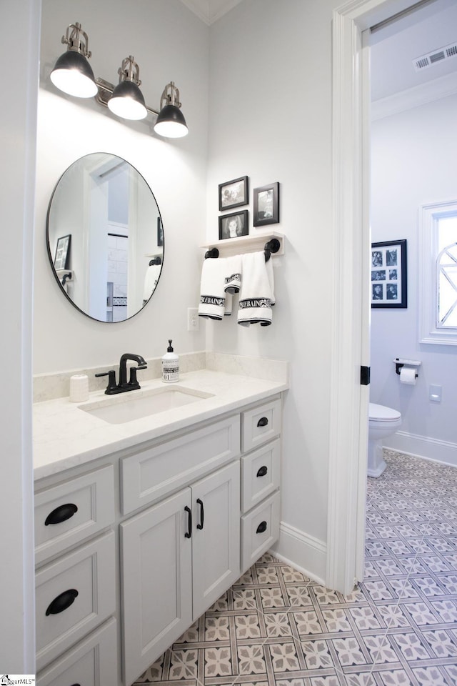 bathroom with visible vents, baseboards, vanity, and toilet