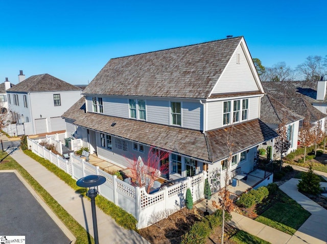 view of front of home featuring a shingled roof, fence private yard, driveway, and a porch