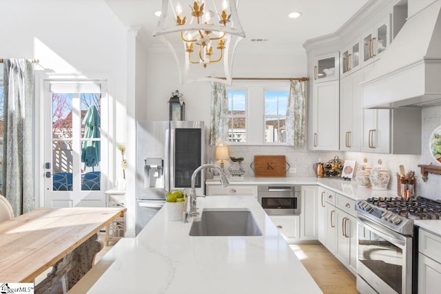 kitchen featuring tasteful backsplash, appliances with stainless steel finishes, crown molding, premium range hood, and a sink