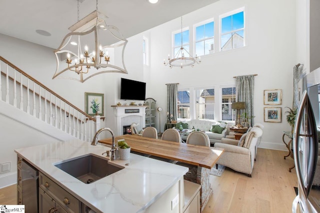 kitchen featuring stainless steel appliances, a fireplace, a sink, open floor plan, and an inviting chandelier