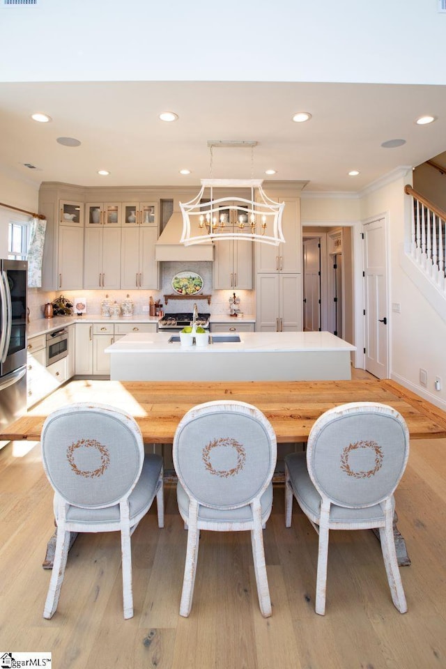 kitchen featuring a sink, light countertops, tasteful backsplash, an island with sink, and smart refrigerator