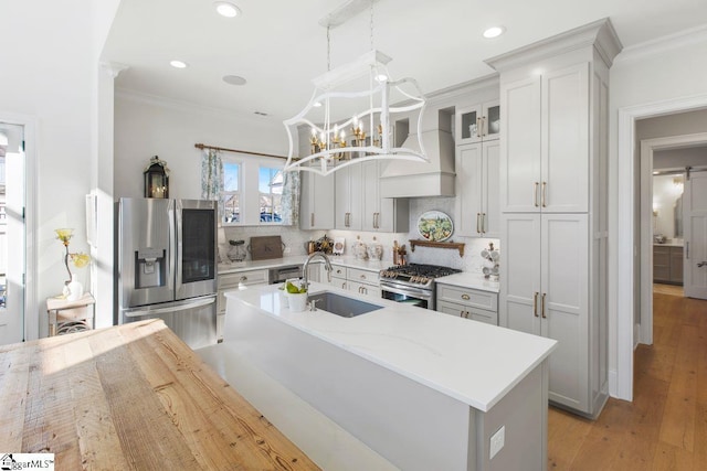 kitchen featuring a sink, premium range hood, appliances with stainless steel finishes, and crown molding