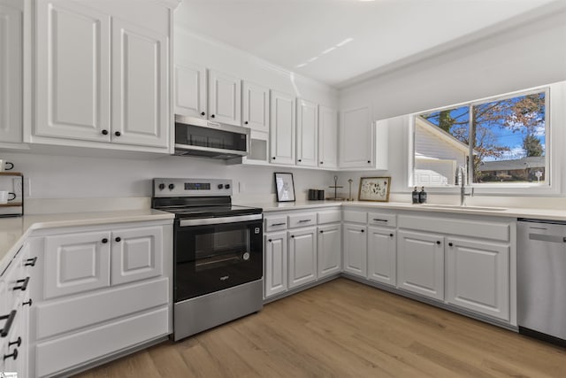 kitchen featuring light wood finished floors, light countertops, appliances with stainless steel finishes, white cabinets, and a sink