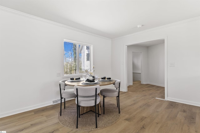 dining space featuring ornamental molding, visible vents, light wood-style flooring, and baseboards