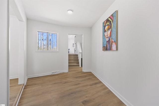 hall featuring light wood-type flooring, baseboards, and visible vents