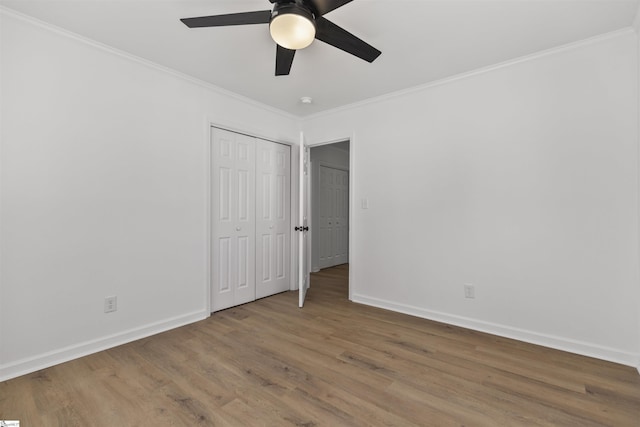 unfurnished bedroom featuring baseboards, a closet, wood finished floors, and crown molding