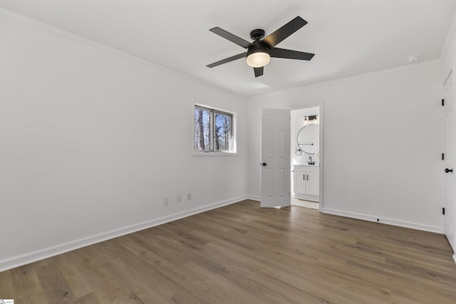 spare room with baseboards, ceiling fan, wood finished floors, crown molding, and a sink