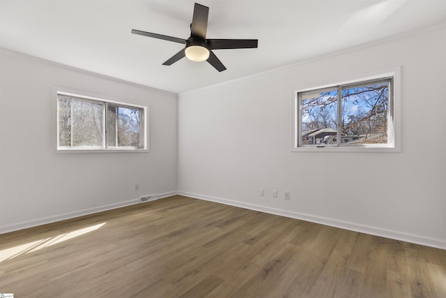 unfurnished room featuring visible vents, baseboards, a wealth of natural light, and wood finished floors