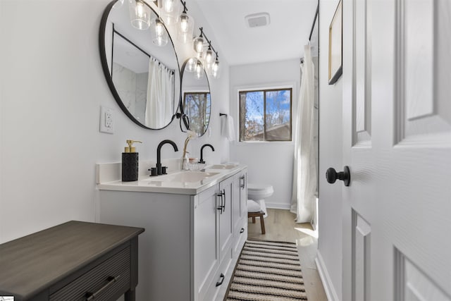 bathroom featuring baseboards, vanity, toilet, and wood finished floors