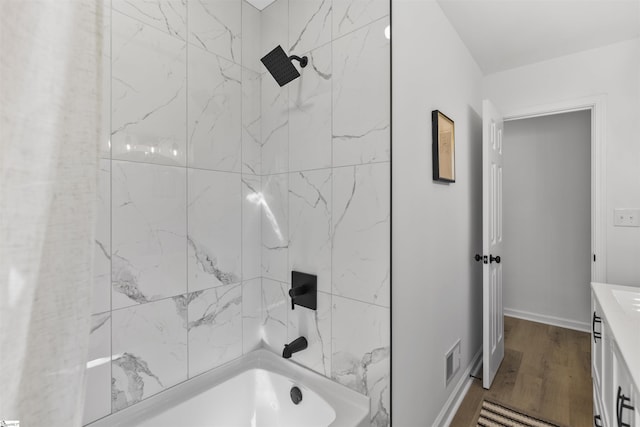 full bathroom featuring visible vents, washtub / shower combination, vanity, wood finished floors, and baseboards