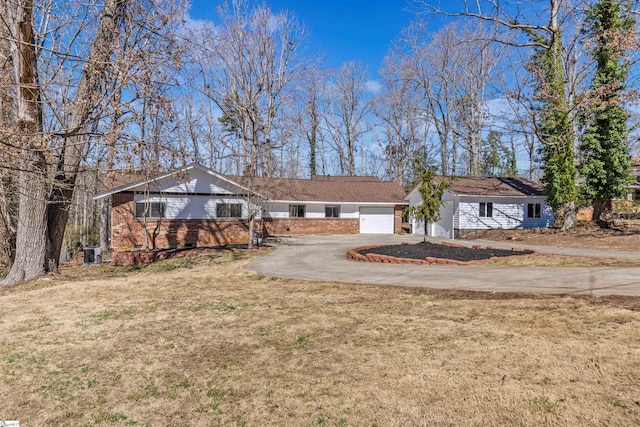 ranch-style house featuring a front yard, brick siding, driveway, and an attached garage