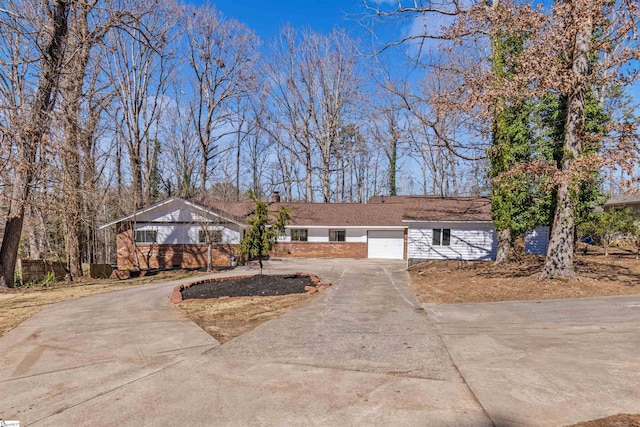 ranch-style house featuring a garage, brick siding, driveway, and a chimney