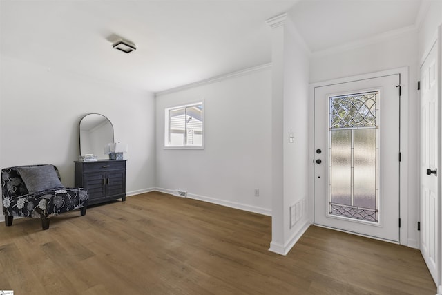 foyer entrance with crown molding, visible vents, and wood finished floors