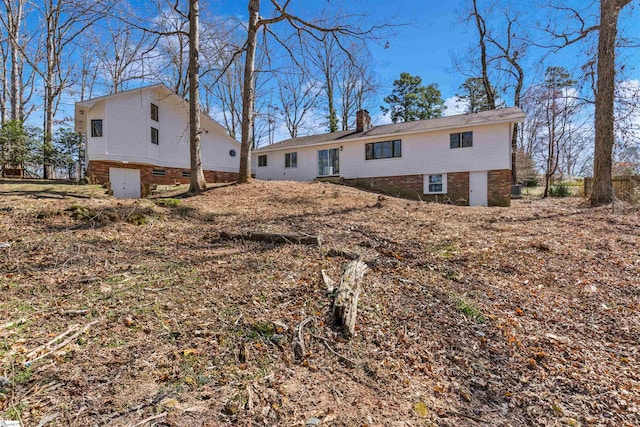 back of house featuring a chimney and brick siding