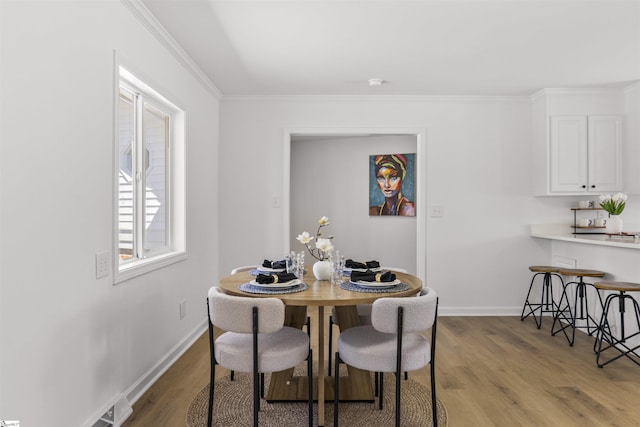 dining space featuring baseboards, wood finished floors, and ornamental molding