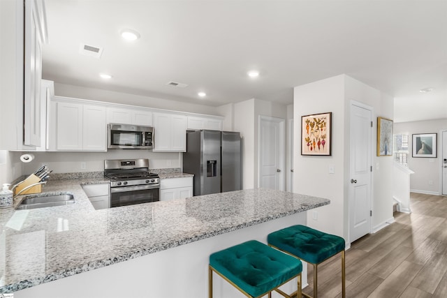 kitchen with visible vents, appliances with stainless steel finishes, a sink, light wood-type flooring, and a peninsula