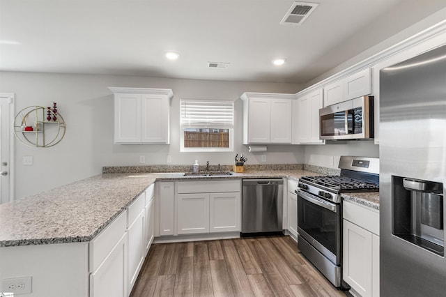 kitchen with a peninsula, visible vents, stainless steel appliances, and a sink