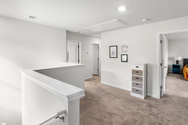 hallway with visible vents, carpet floors, attic access, and baseboards