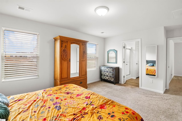 bedroom featuring baseboards, visible vents, and light colored carpet