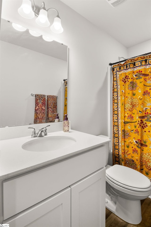 bathroom featuring a chandelier, curtained shower, toilet, wood finished floors, and vanity