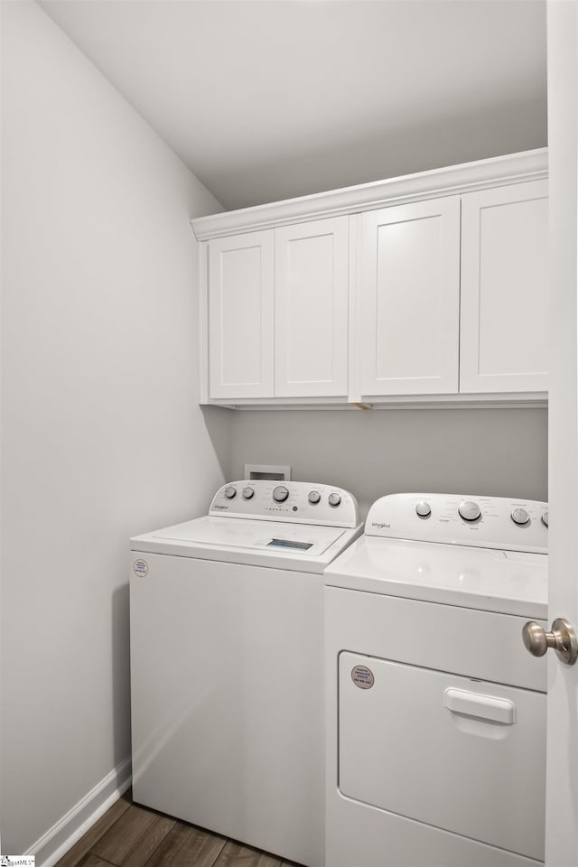 washroom featuring baseboards, cabinet space, dark wood finished floors, and washing machine and clothes dryer